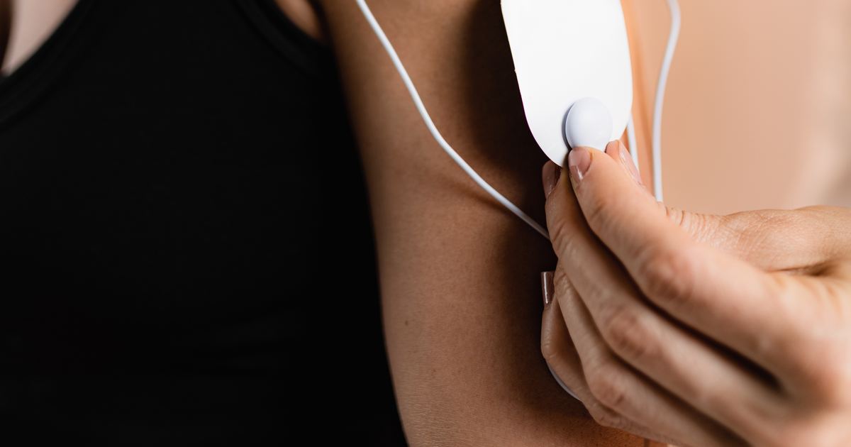 Elektroden einer Reizstromtherapie werden an Schulter und Arm einer Patientin angebracht
