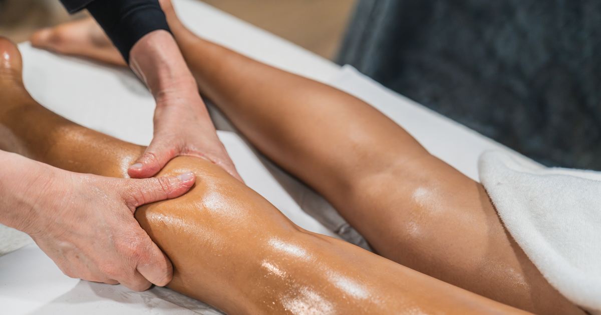 Physiotherapeutin führt eine manuelle Lymphdrainage am Bein einer Patientin durch