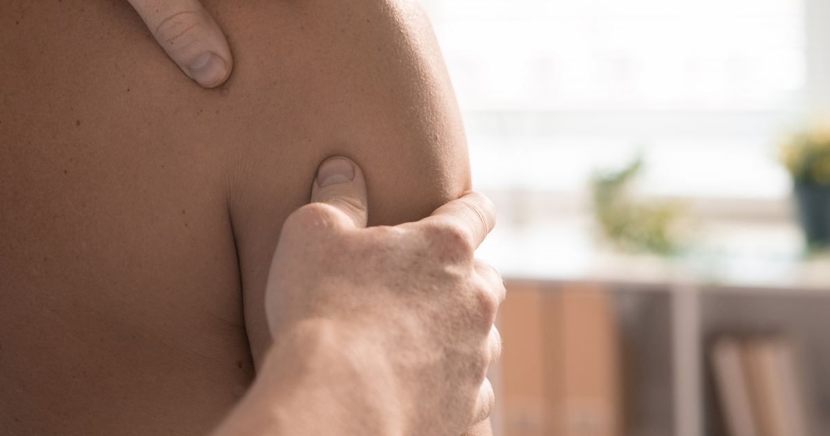 Physiotherapeut mobilisiert mit gezielten Handgriffen das Schultergelenk eines Patienten